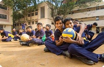 Students with volleyballs on the school playground
